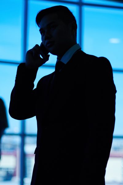 Outlines of business team standing against window with leader speaking on the phone in front